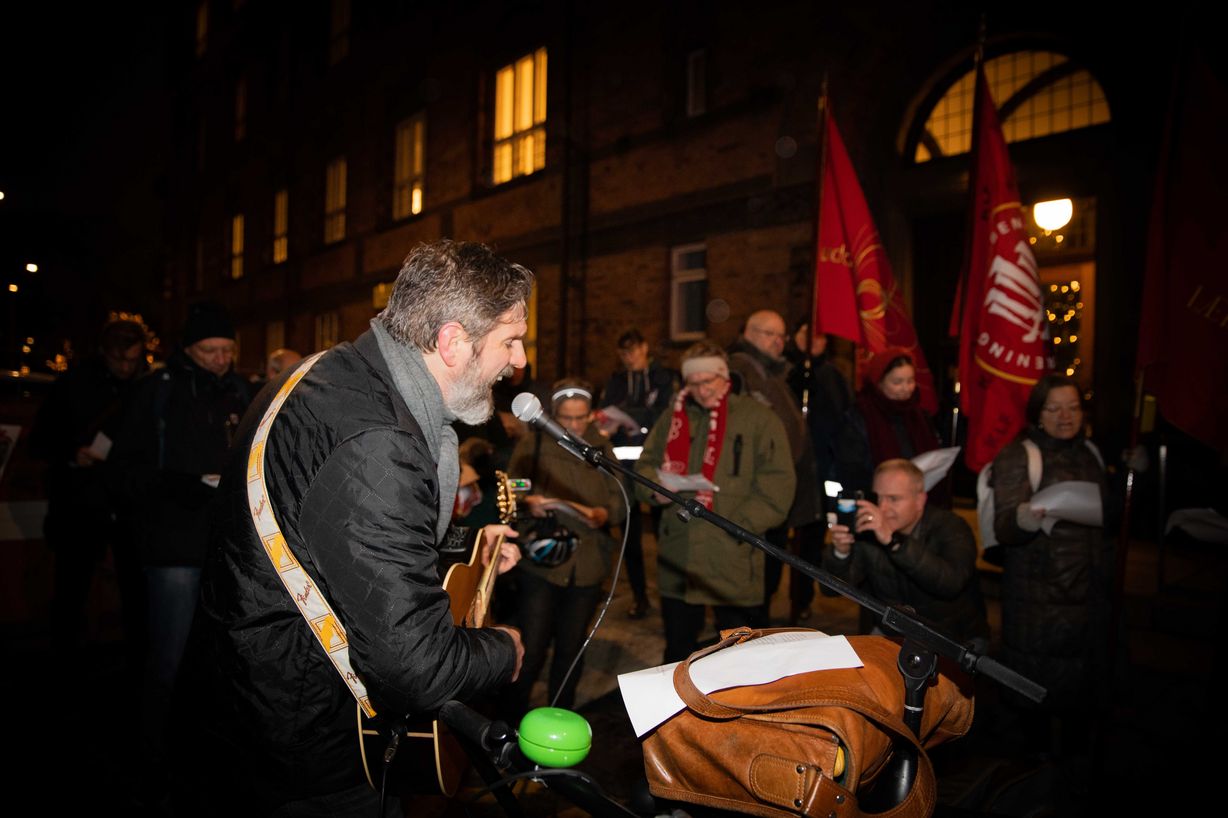 Tillidsrepræsentant og trubadur Klaus Møller varmede forsamlingen af fagforeningsfolk med forskellige velvalgte sange til lejligheden akkompangeret af politiets blå blink mod aftenhimlen. Foto: Jan Klint Poulsen Tillidsrepræsentant og trubadur Klaus Møller varmede forsamlingen af fagforeningsfolk med forskellige velvalgte sange til lejligheden akkompangeret af politiets blå blink mod aftenhimlen. Foto: Jan Klint Poulsen